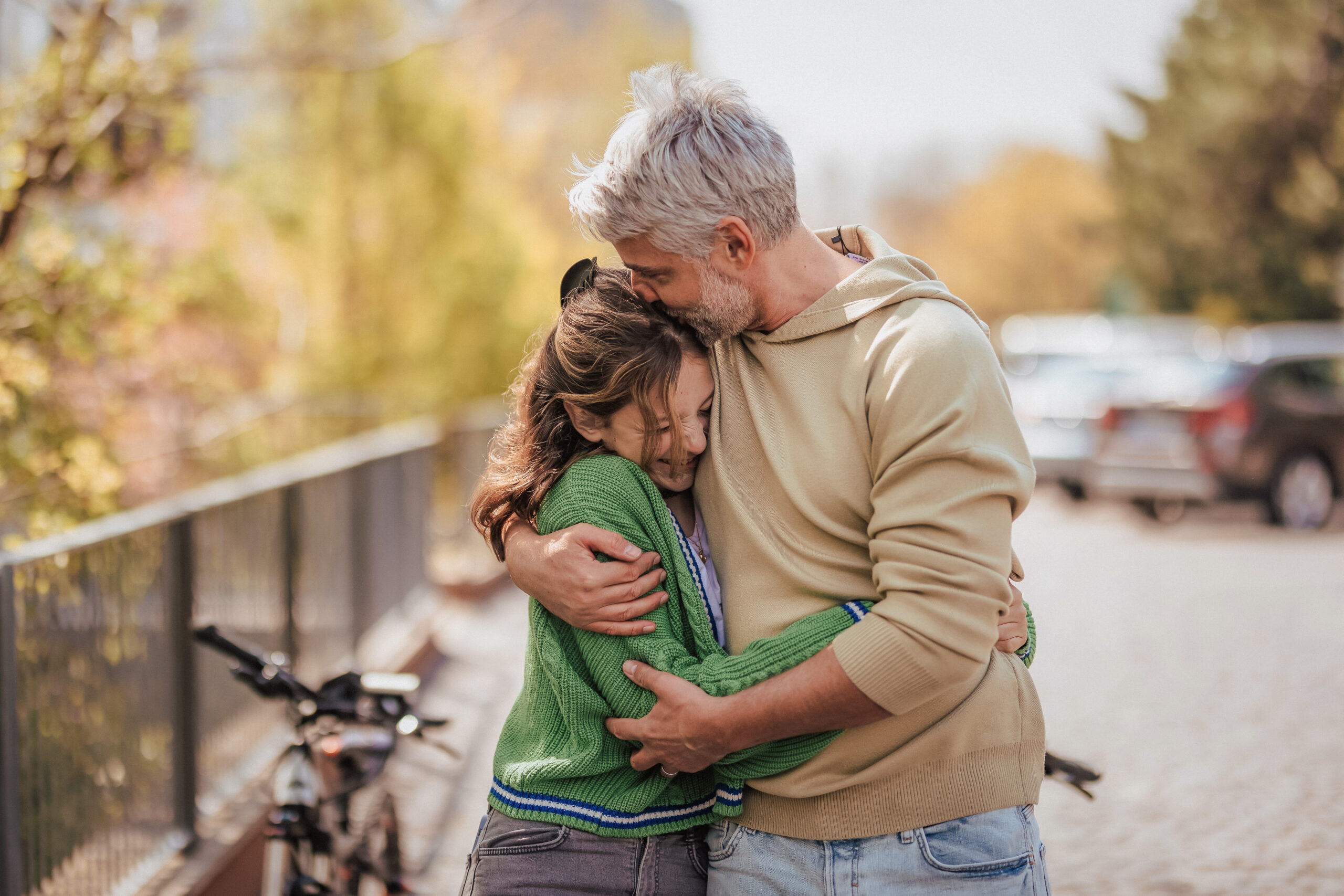 teenage daughter hugging her father outside in town when spending time together.